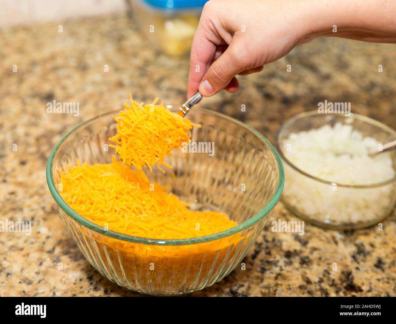 Sessole per mano di formaggio Cheddar grattugiato dalla ciotola Foto Stock