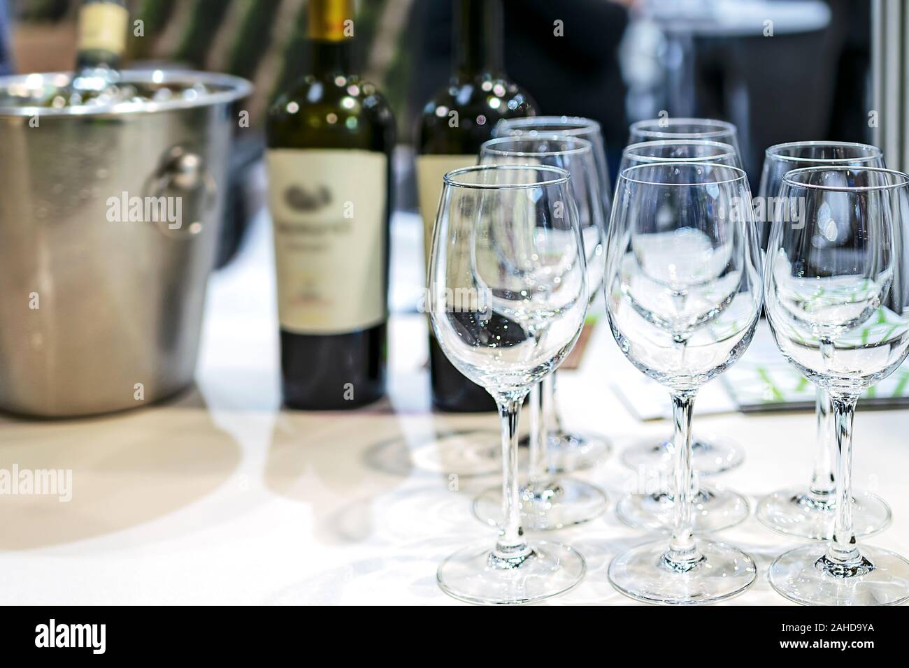Fila di shining bicchieri di vino con bottiglie di vino sullo sfondo nel ristorante ( copia spazio) Foto Stock