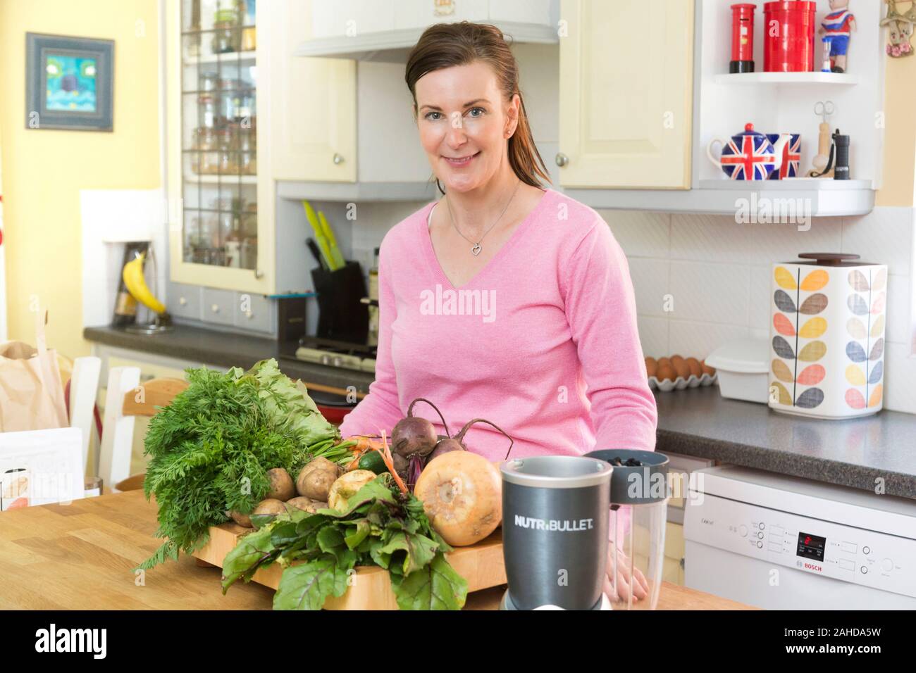 Donna con naturali freschi cibi organici e nutribullet in cucina Foto Stock