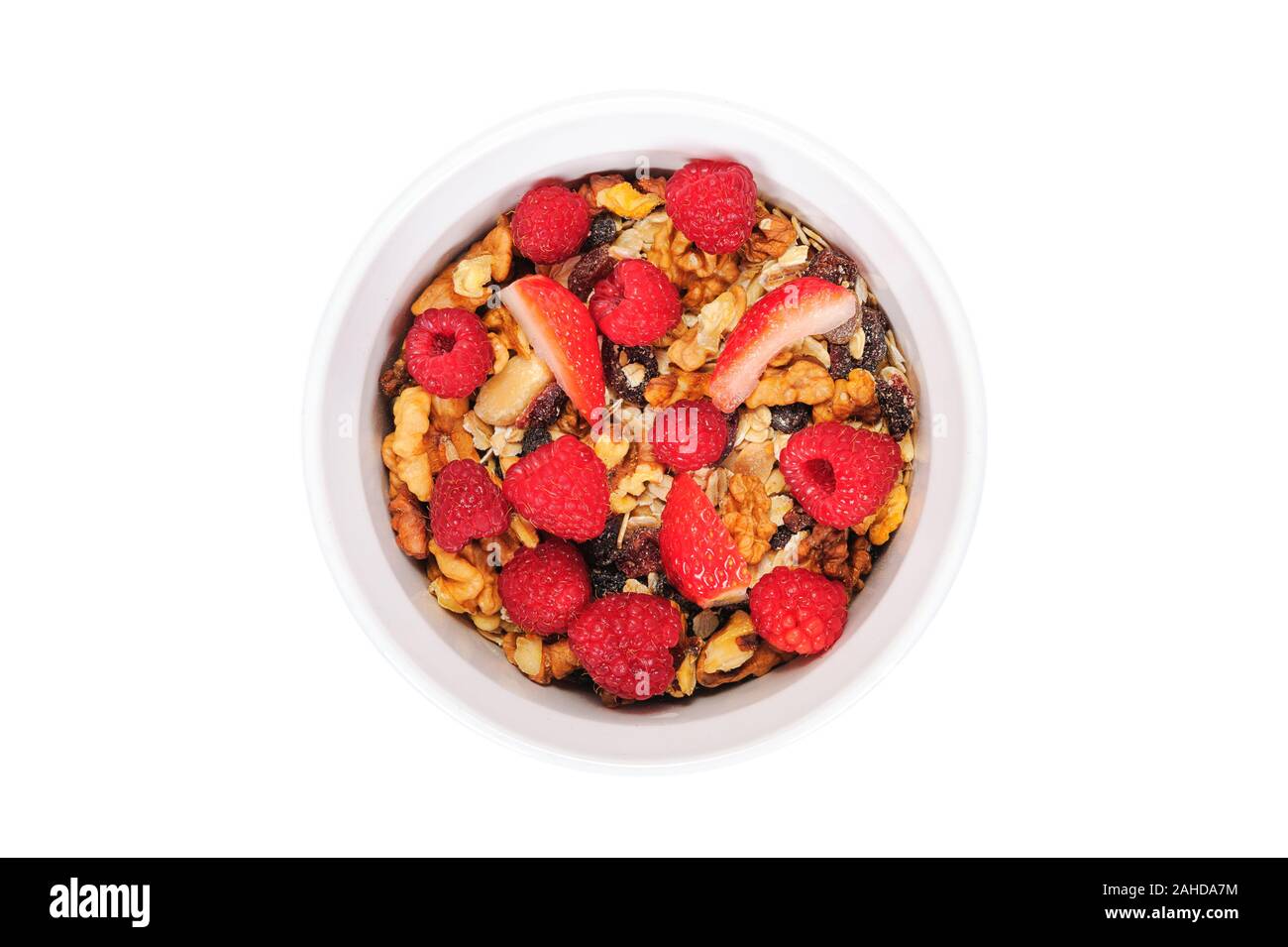 Vista dall'alto di una casalinga di muesli biologico con avena, dadi, lamponi e fragole in una ciotola bianco Foto Stock