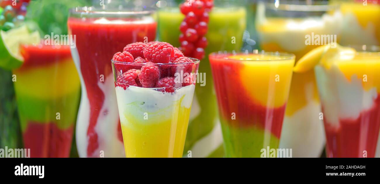 Ampia banner pubblicitario di varie frutta fresca bevande in bicchieri con lamponi frullati in primo piano Foto Stock