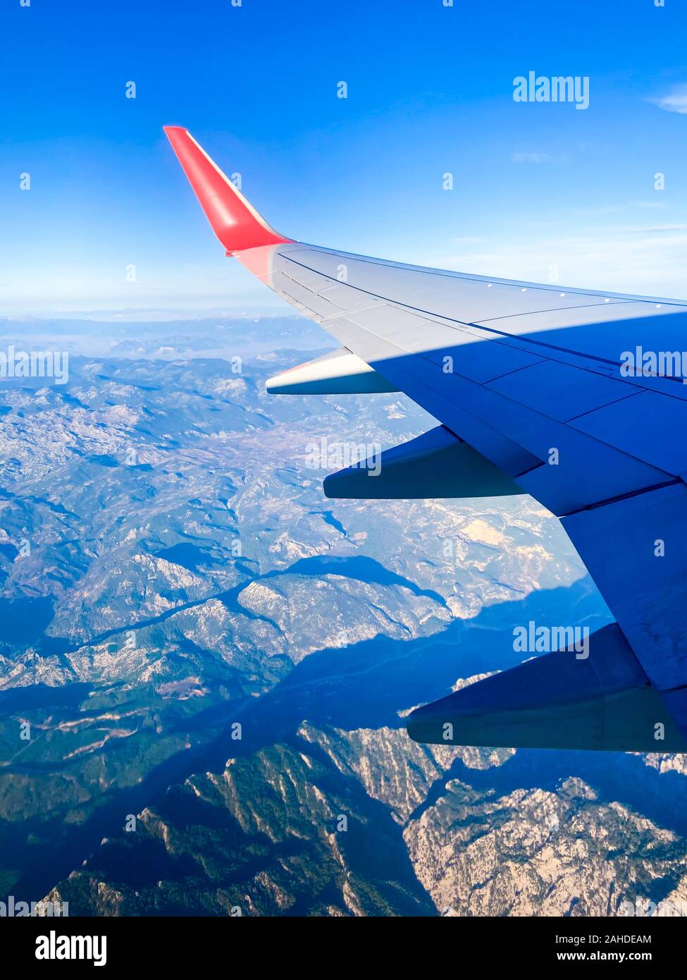 La vista dalla finestra aereo sulle nuvole e montagne. Dalla finestra è possibile vedere l'ala del velivolo. Mattina. Il volo e il viaggio. Top v Foto Stock