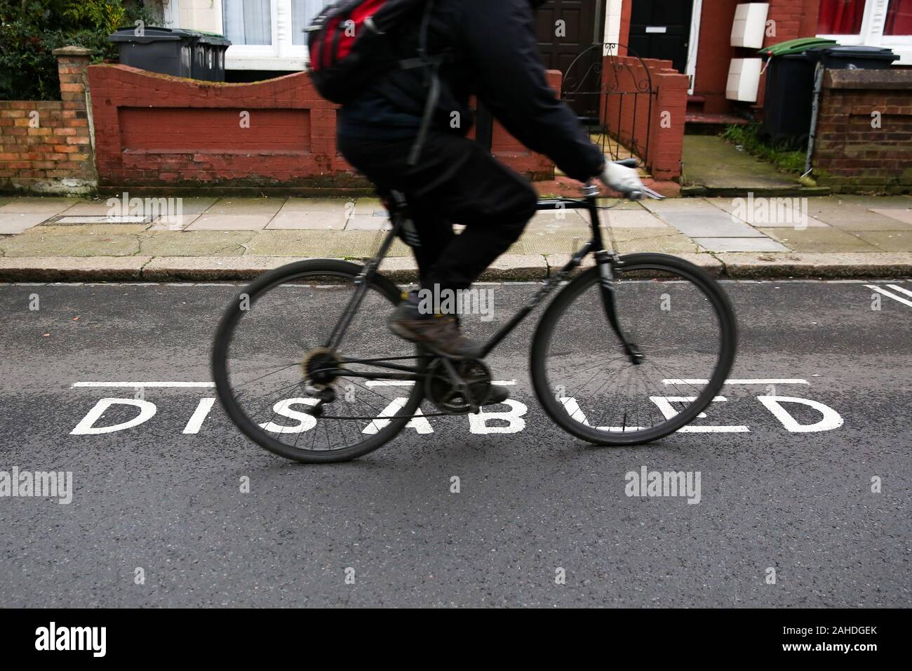 Un ciclista scorre da un parcheggio disabili bay nel nord di Londra.Migliaia di persone con disabilità nascoste sono state date blue badge permessi di parcheggio poiché le nuove regole sono state introdotte. Foto Stock