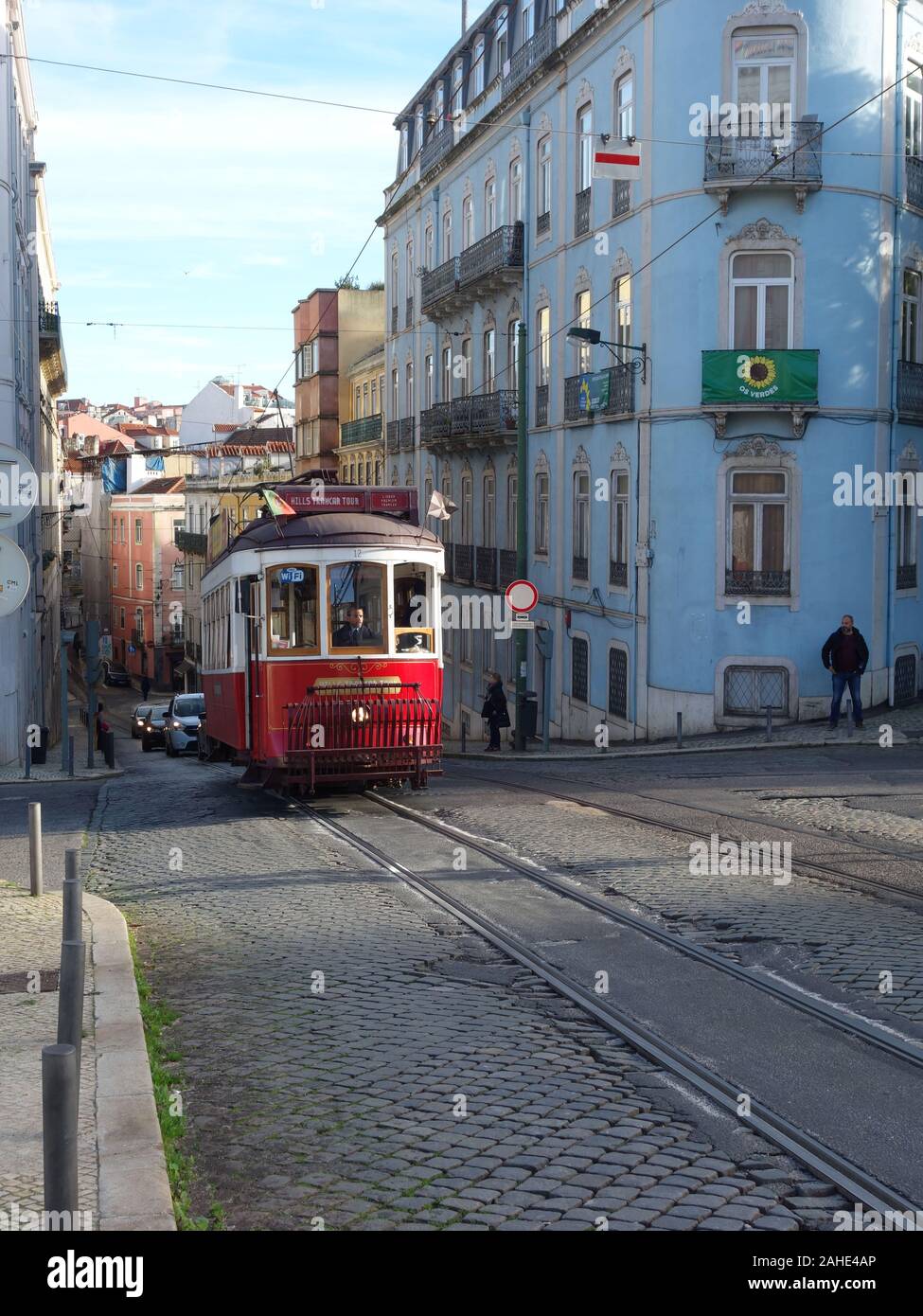 Red tram a Lisbona illuminata da un raggio di sole in background la città in discesa Foto Stock