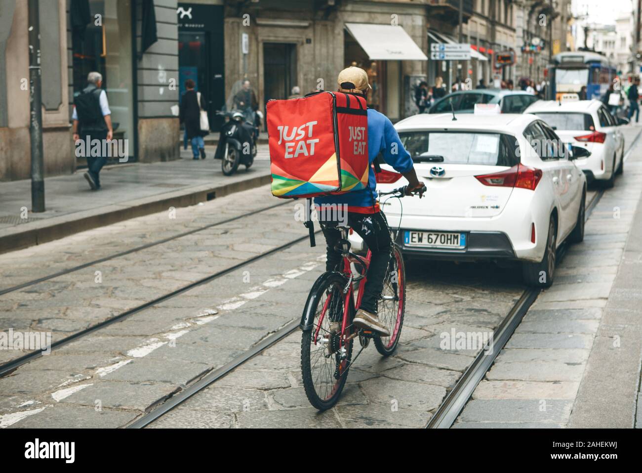 L'Italia, Milano, 30 Maggio 2019: Il cibo è deliveryman escursioni in bicicletta lungo la strada nel traffico pesante. Foto Stock