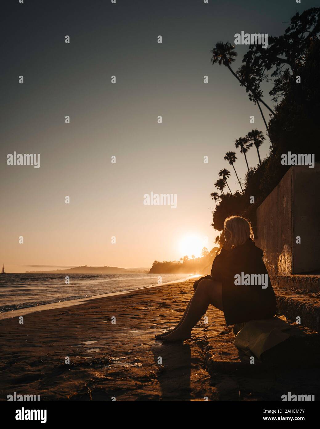 Le donne orologi il tramonto sulla spiaggia Foto Stock