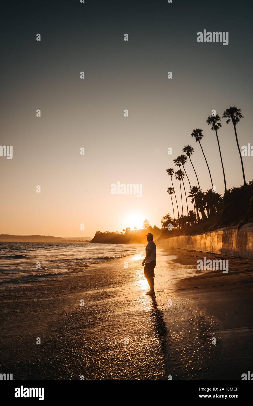 Gli uomini orologi il tramonto sulla spiaggia Foto Stock