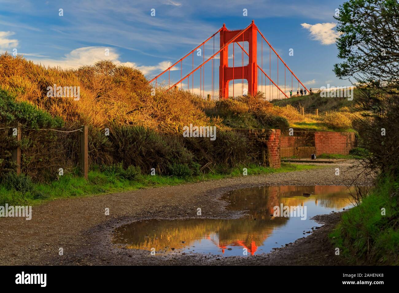 Panorama di San Francisco Golden Gate bridge in Marin Headlands California riflettendo in una pozzanghera dopo la pioggia con soffici nuvole in background Foto Stock