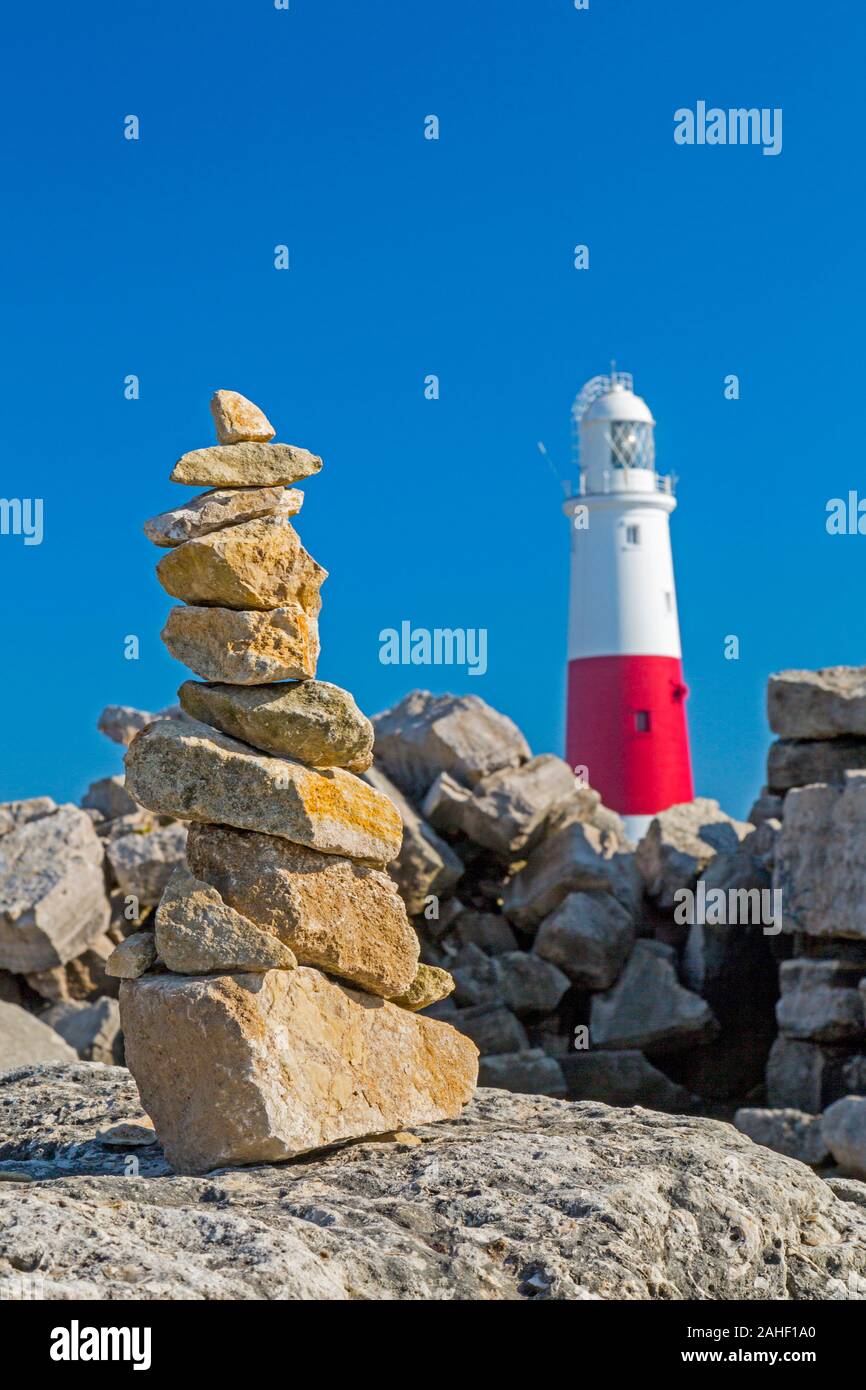 Un mucchio di pietre di bilanciamento e il faro di Portland Bill, Dorset, England, Regno Unito Foto Stock
