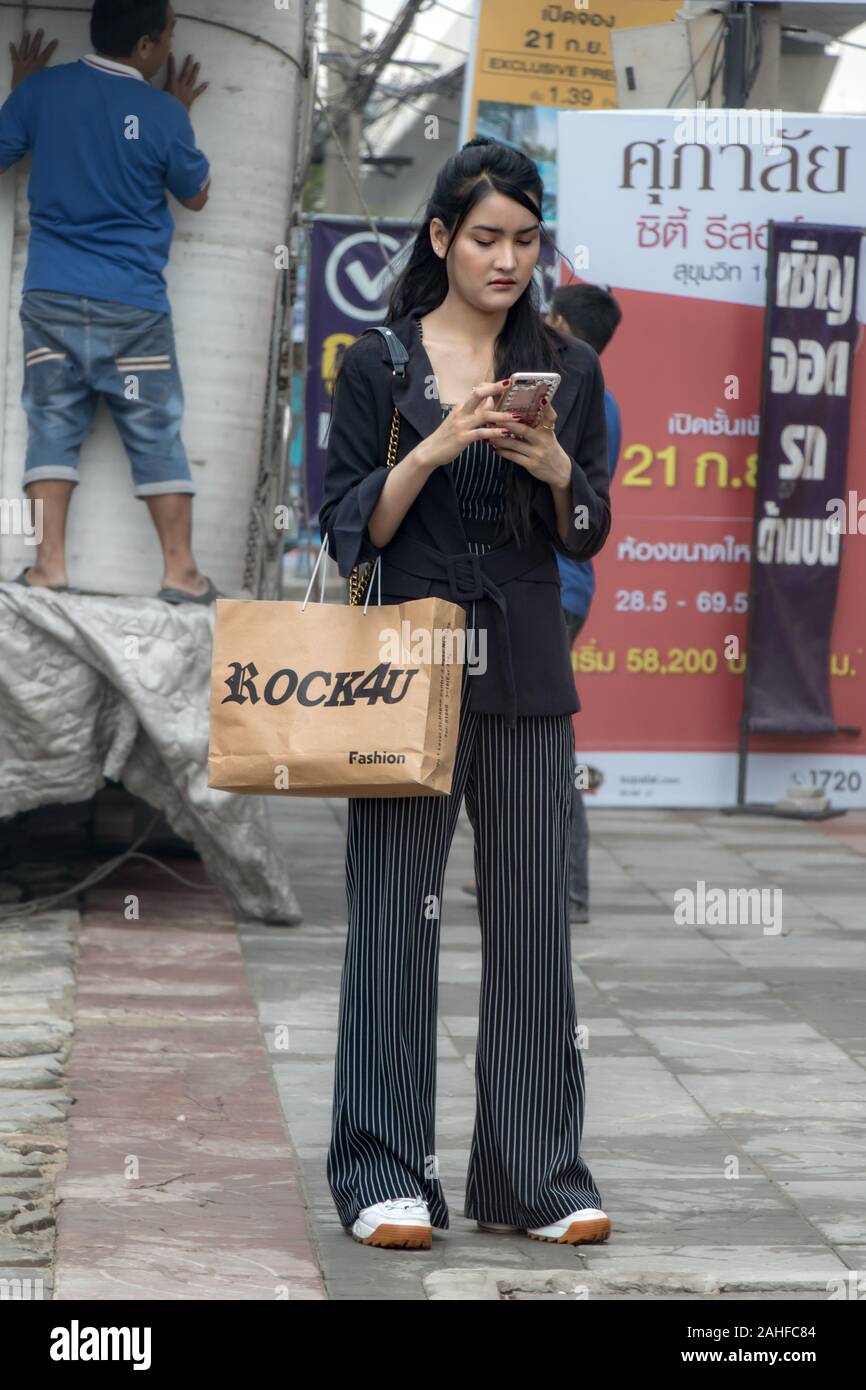 SAMUT PRAKAN, Thailandia, Sep 21 2019, la giovane donna si erge sul marciapiede con il sacchetto e il telefono cellulare in mano. Foto Stock