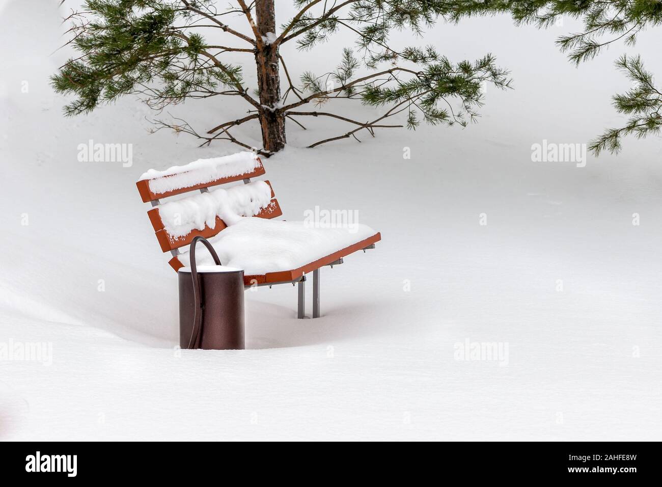 Una coperta di neve abbandonati e dimenticati una panchina nel parco per il quale non vi è un unico tracciato Foto Stock