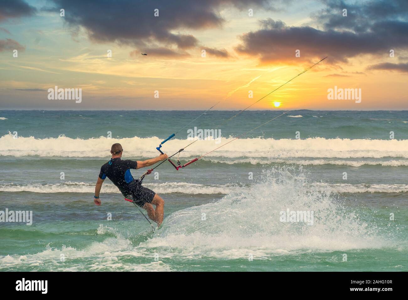 Maschio di kite surfer a giocare con le onde al tramonto al mare tropicale Foto Stock