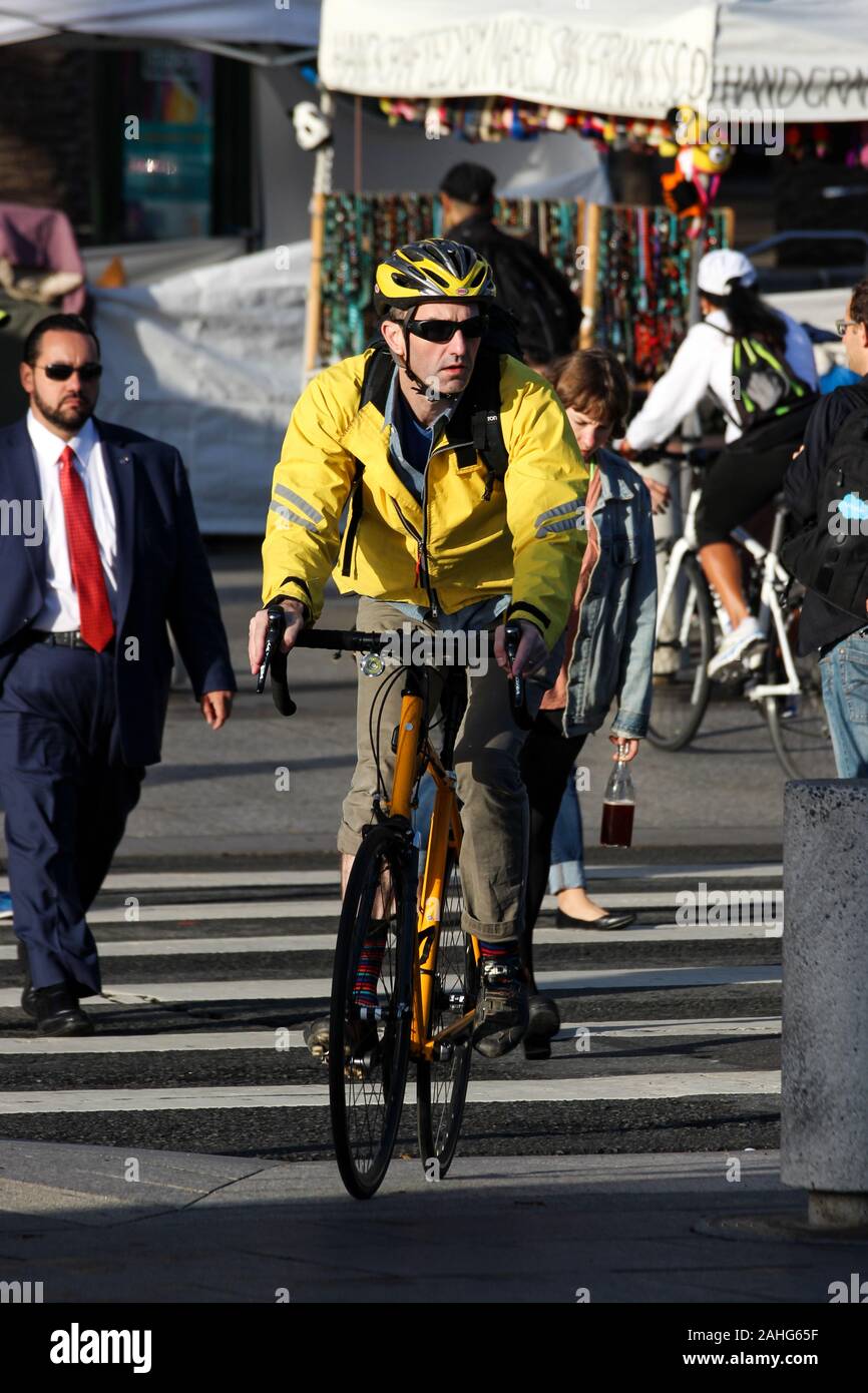 Maschio di " commuters " Bicicletta attraversando via nella luce del mattino Foto Stock