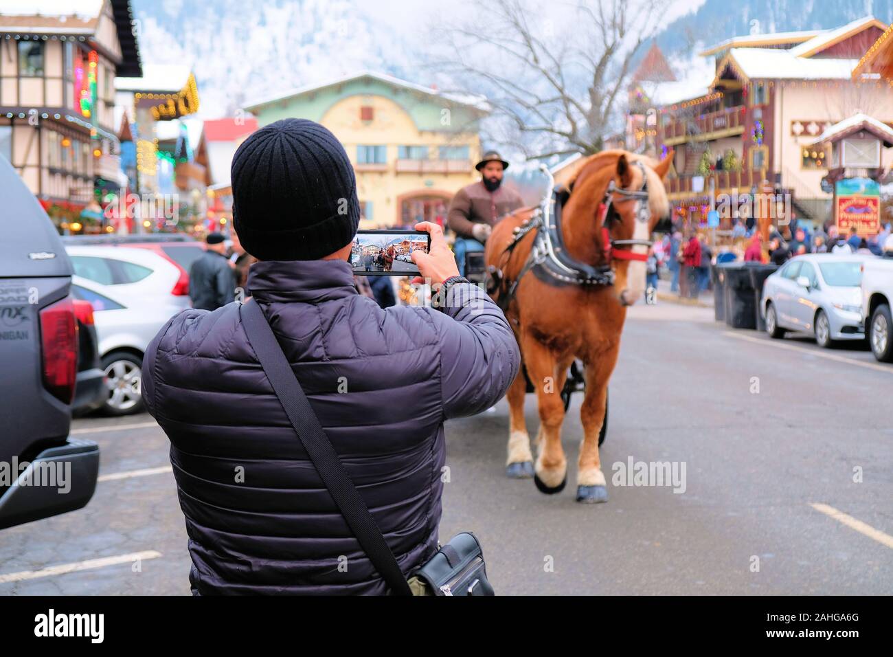 Turistica prendendo un telefono cellulare foto di una carrozza trainata da cavalli; immagine all'interno di un'immagine, turismo invernale in Leavenworth, nello Stato di Washington, USA. Foto Stock