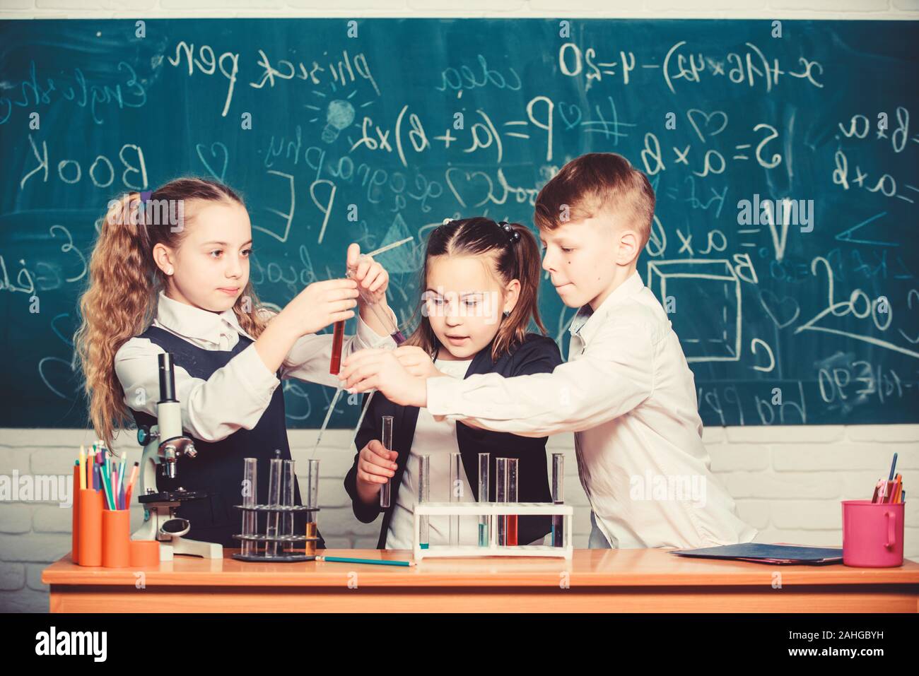 Gli studenti non esperimenti di biologia con microscopio. Microscopio di chimica. Microscopio di laboratorio. giorno. I bambini Imparare la chimica in laboratorio scolastico. I bambini piccoli in laboratorio. Letali e pericolose. Foto Stock