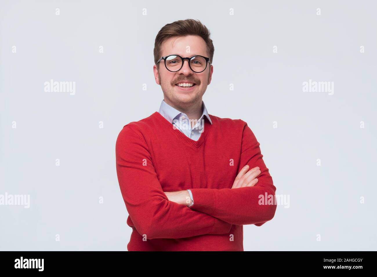 Uomo in felpa rossa e i bicchieri in piedi nella parte anteriore della fotocamera, sentimento positivo e fiducioso Foto Stock