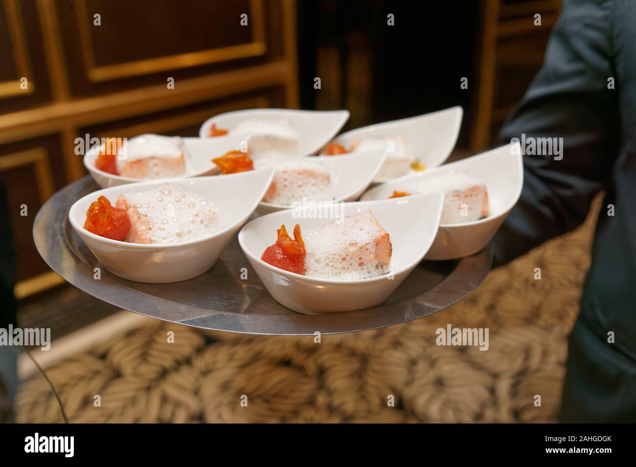 Il cameriere porta il vassoio con banchetti con piastre di cibo - salmone e salsa schiumoso Foto Stock