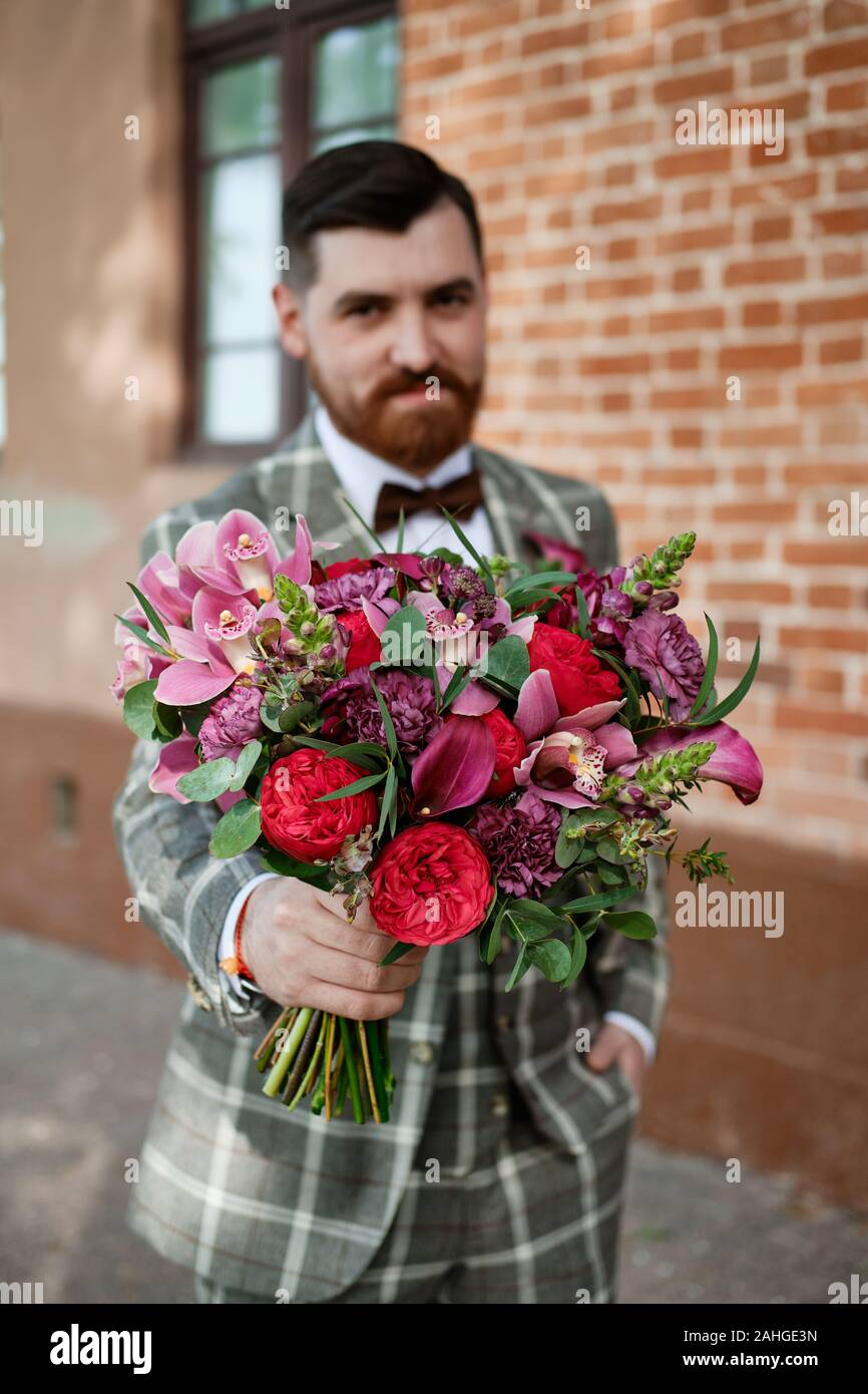 Uomo vestito elegante completo Azienda bouquet di fiori Foto stock - Alamy