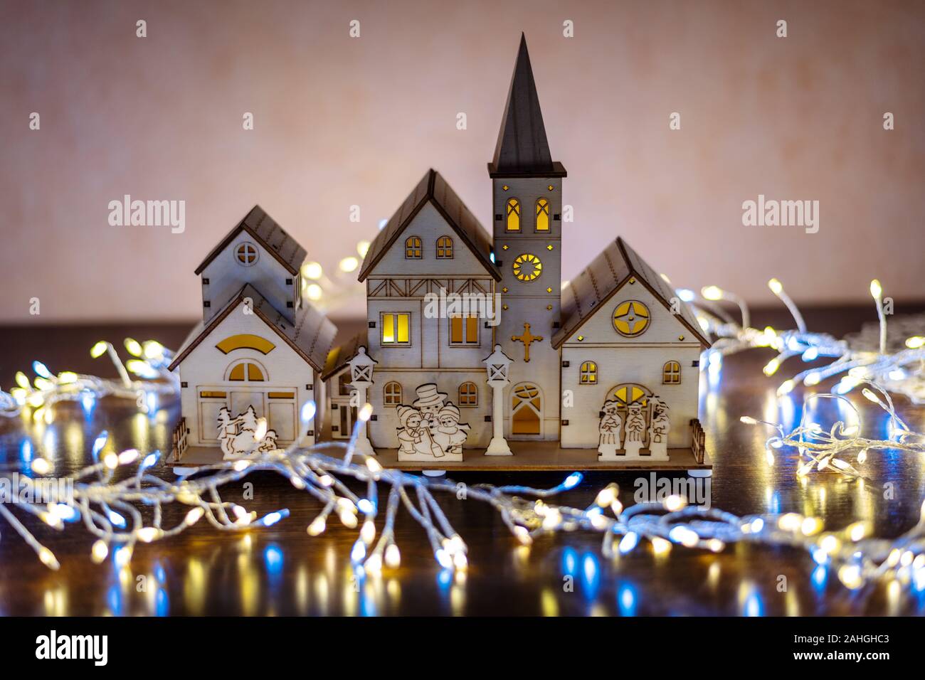 Sfondo di natale con un villaggio in legno illuminato, circondato da una luce led tinsel. Foto Stock