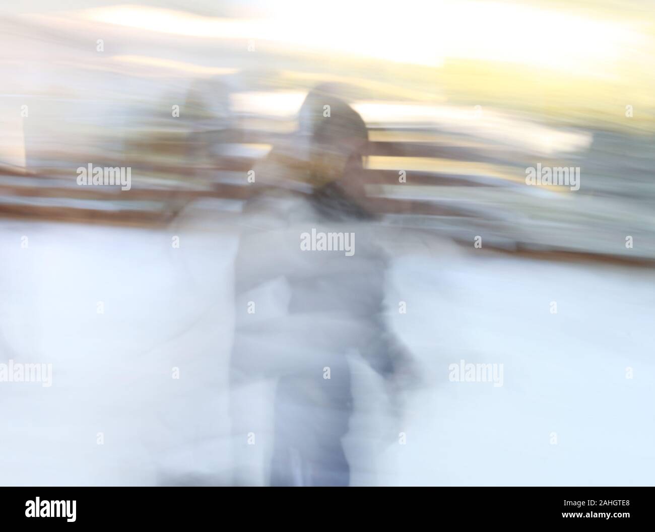 Una foto sfocata di una ragazza bionda con un abito bianco in un campo di neve Foto Stock