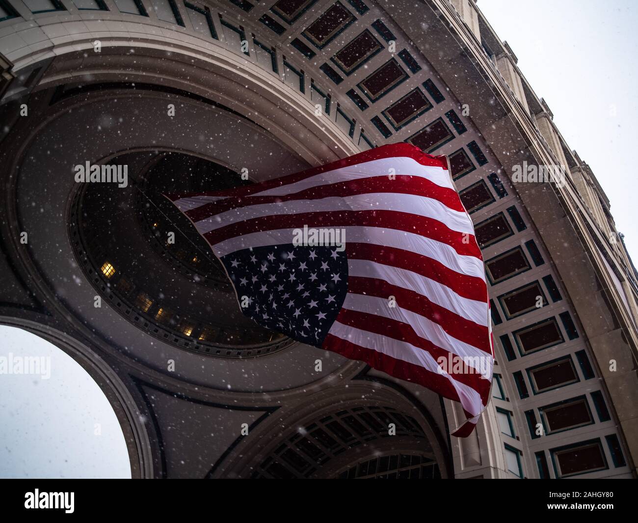 La neve cade intorno alla bandiera americana su una giornata invernale Foto Stock