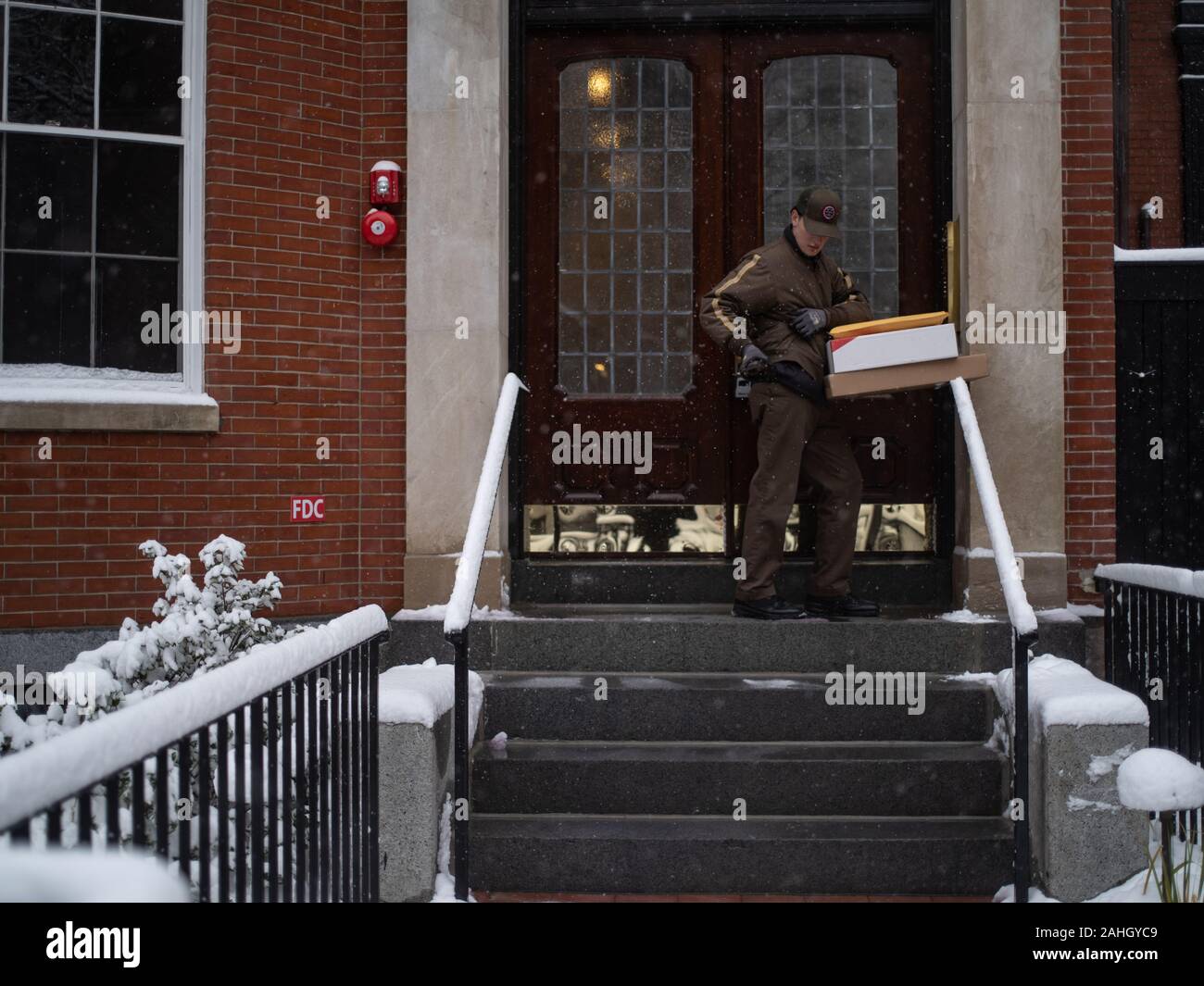 Un uomo di consegna saldi una scatola al di fuori della porta anteriore Foto Stock