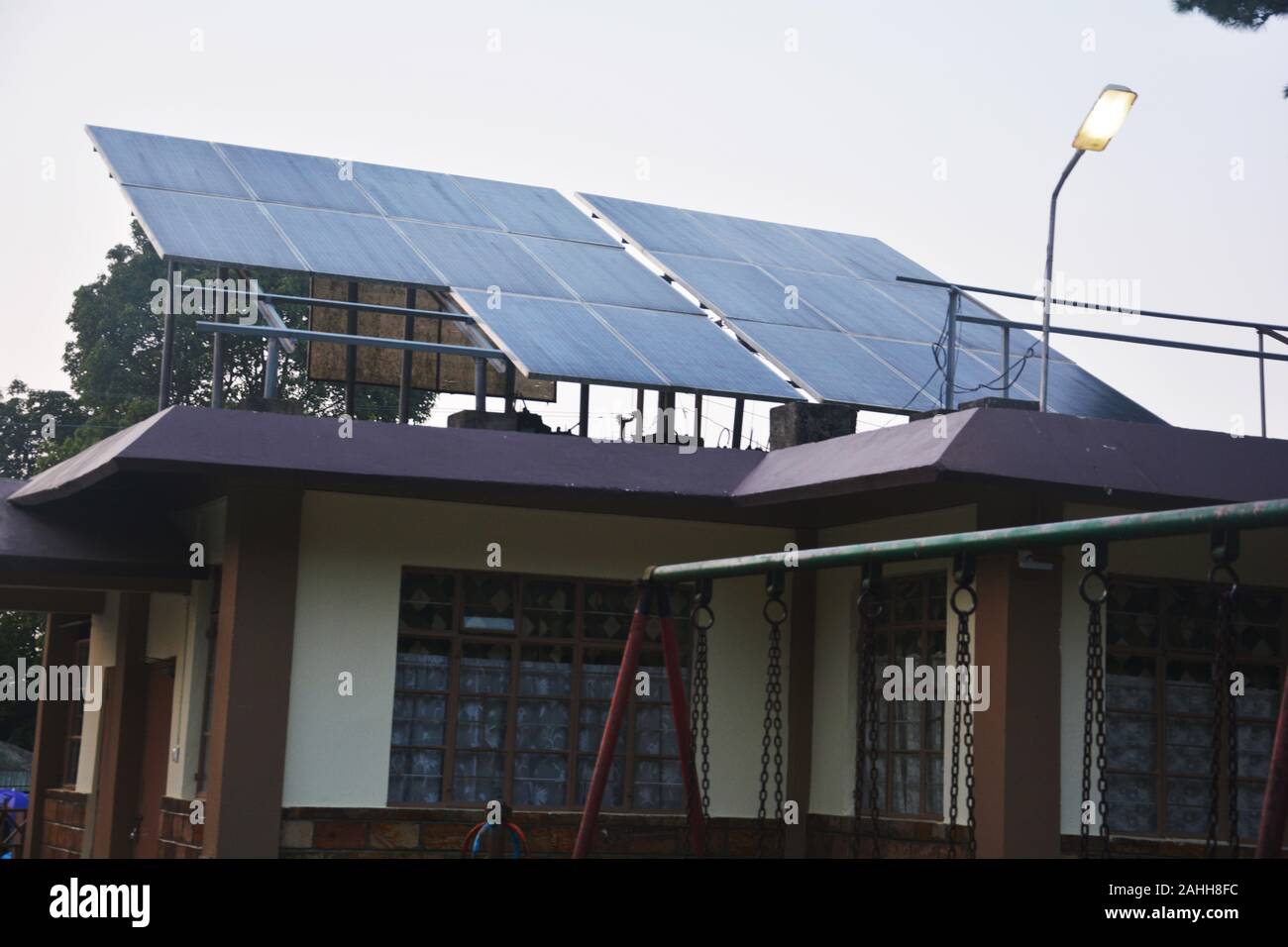 Close up di pannelli solari sul tetto di un edificio pubblico in elefante cade Shillong con grandi finestre di vetro e le catene di una oscillazione fissato sul tubo di ferro Foto Stock