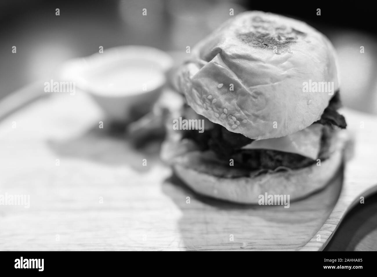 Cheeseburger servita su un tavolo di legno in bianco e nero Foto Stock
