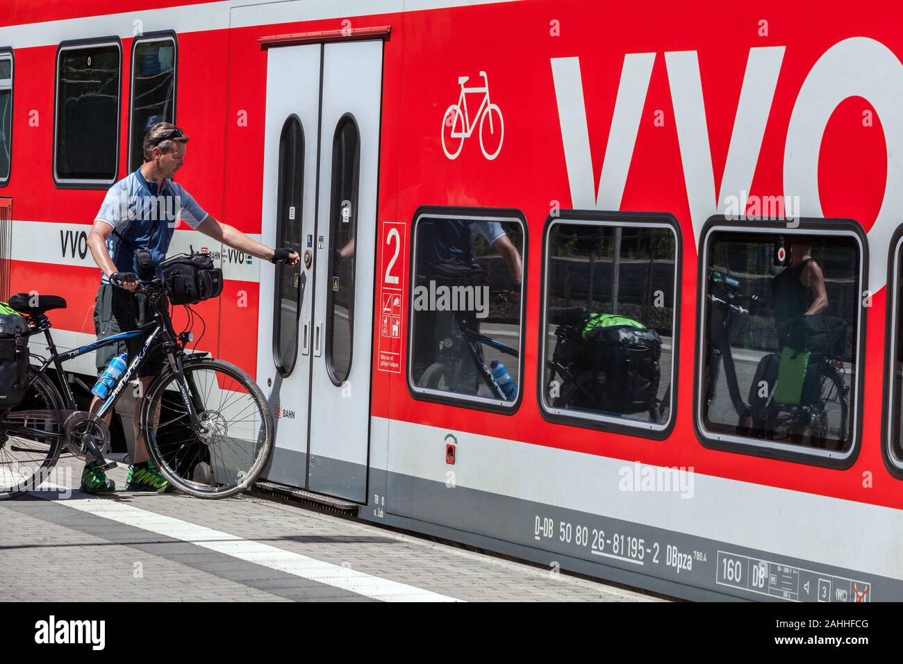 Un uomo con una bicicletta sul viaggio è l'apertura della porta di un treno regionale, Germania uno stile di vita attivo Foto Stock