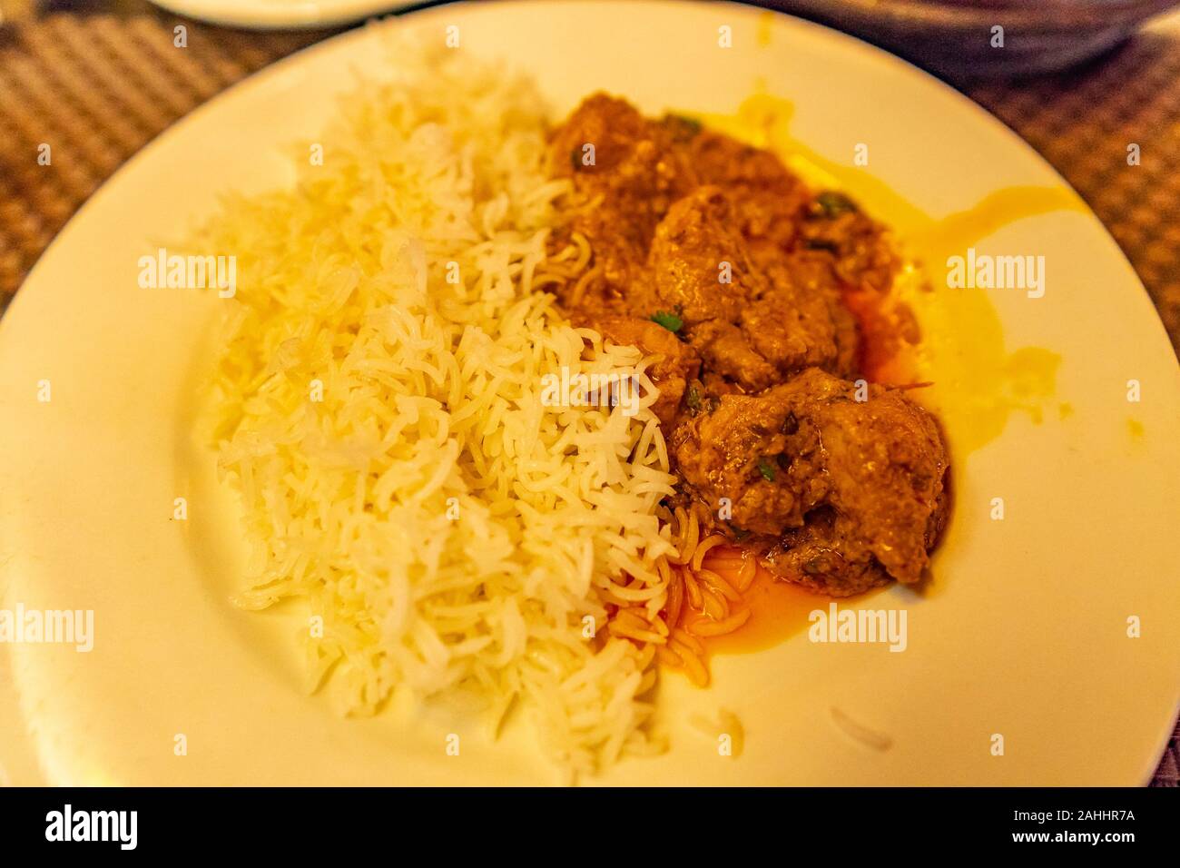 Tradizionale pakistano da acquolina in bocca di Colore Arancione Agnello piccante curry servita con riso Foto Stock