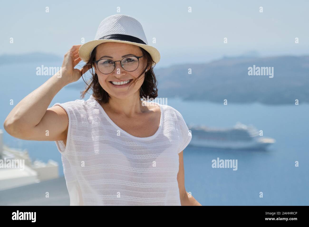 Ritratto di donna di mezza età che viaggiano in crociera di lusso nel Mediterraneo. Donna sorridente guardando la fotocamera sull isola di Santorini, spazio di copia Foto Stock