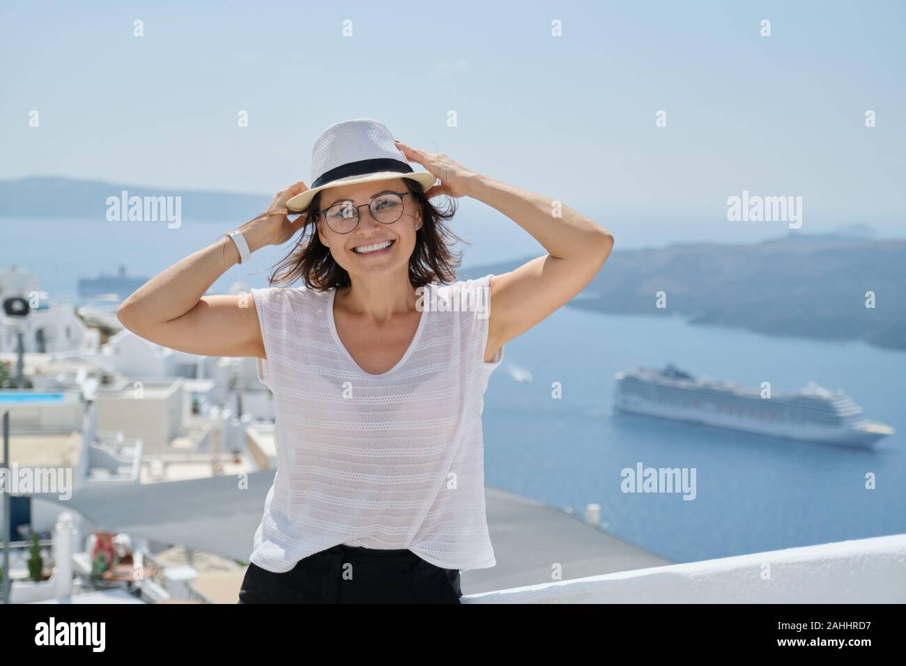 Ritratto di donna di mezza età che viaggiano in crociera di lusso nel Mediterraneo. Donna sorridente guardando la fotocamera sull isola di Santorini, spazio di copia Foto Stock