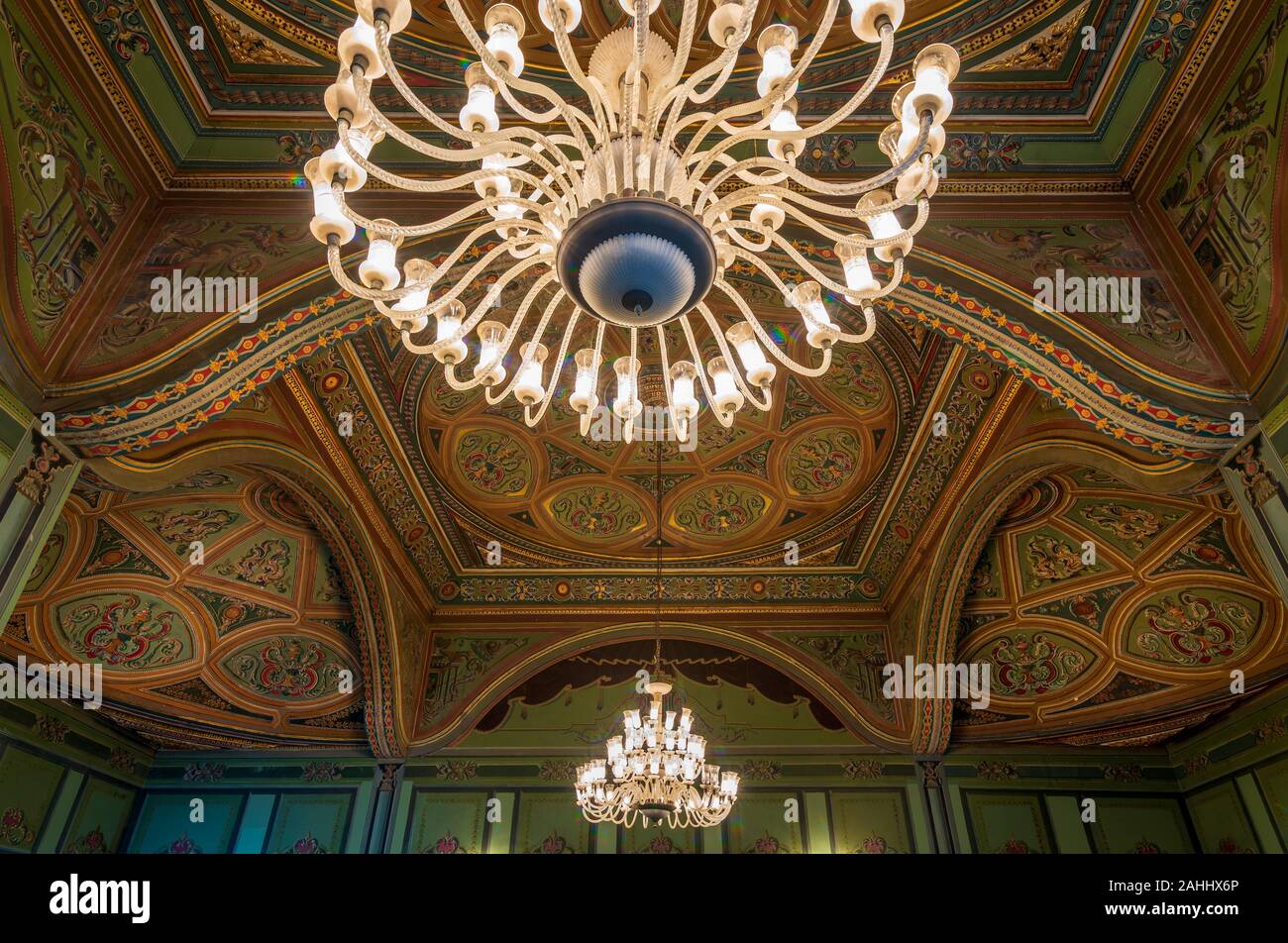 Soffitto a royal era storico palazzo Manasterly decorata con colorate e golden dipinti floreali e grande lampadario illuminato, il Cairo, Egitto Foto Stock
