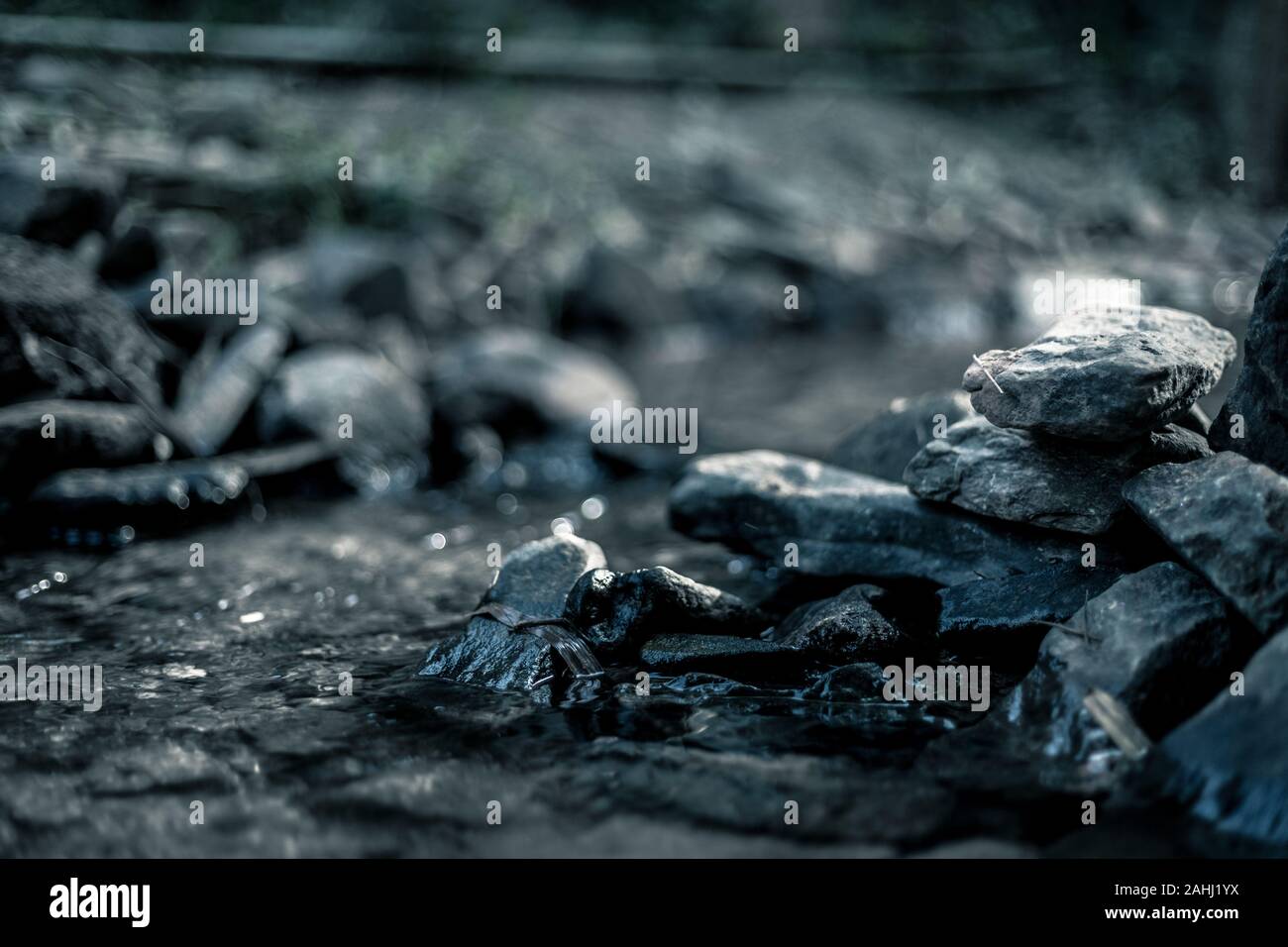 Close up di pietra che uso per rendere weir nel fiume con acqua vapore fluente, realizzati in tono drammatico Foto Stock