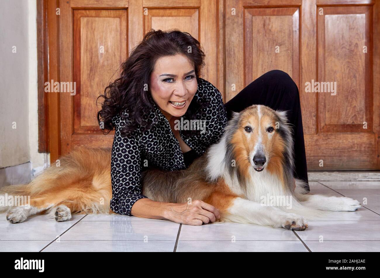 donna che indossa una camicia nera seduta con il suo cane Foto Stock