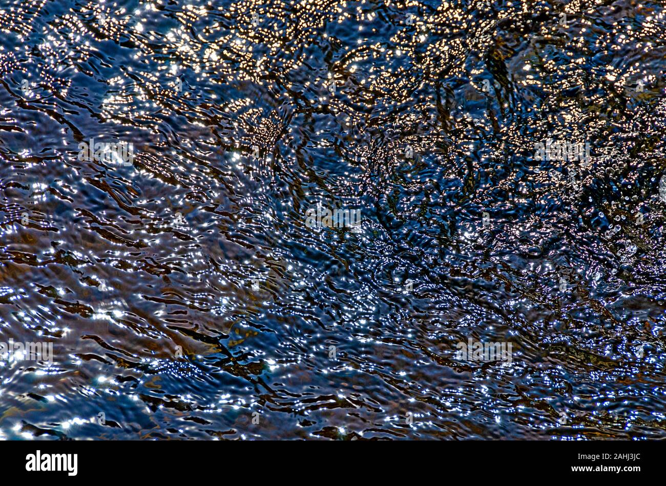 Le onde e i riflessi di luce sulla superficie di un acqua turbolenta Foto Stock