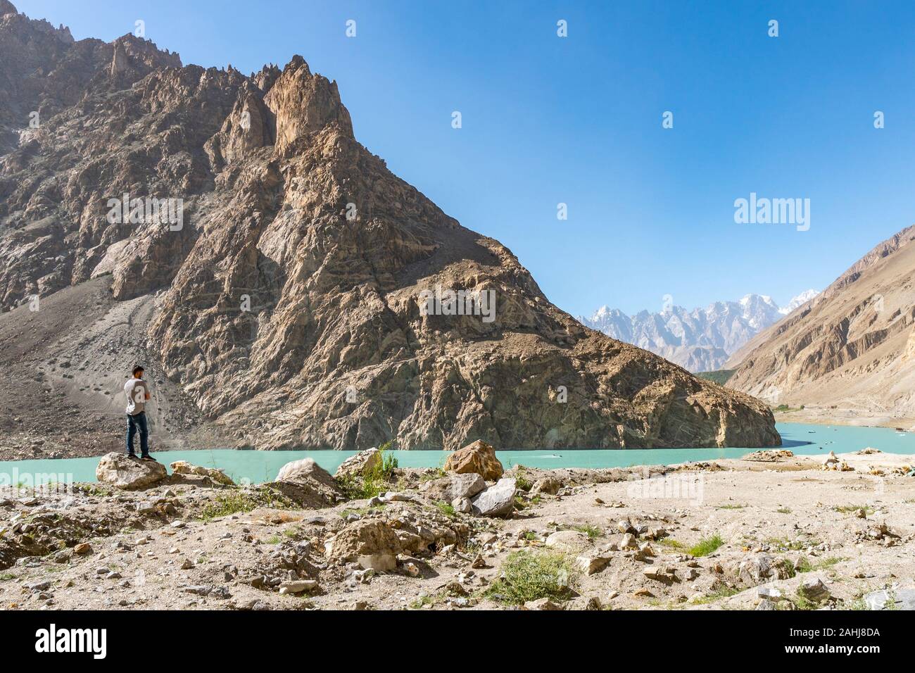 Lago di Attabad paesaggio pittoresco panorama mozzafiato con un pakistano giovane uomo godendosi il panorama su un soleggiato Blue Sky giorno Foto Stock