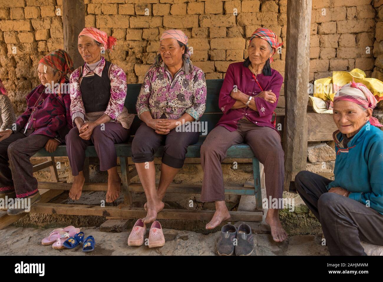 Le donne anziane di Yi gruppo etnico riposo nel villaggio Cangtai quali funzioni tradizionali abitazioni di terracotta - tuzhangfang, Honghe, Yunnan in Cina. Foto Stock