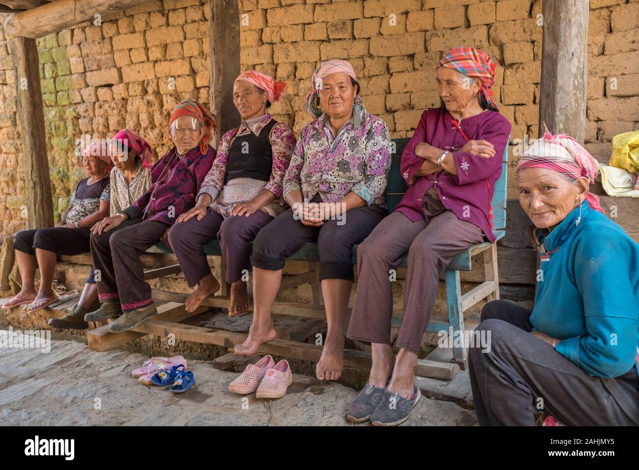 Le donne anziane di Yi gruppo etnico riposo nel villaggio Cangtai quali funzioni tradizionali abitazioni di terracotta - tuzhangfang, Honghe, Yunnan in Cina. Foto Stock