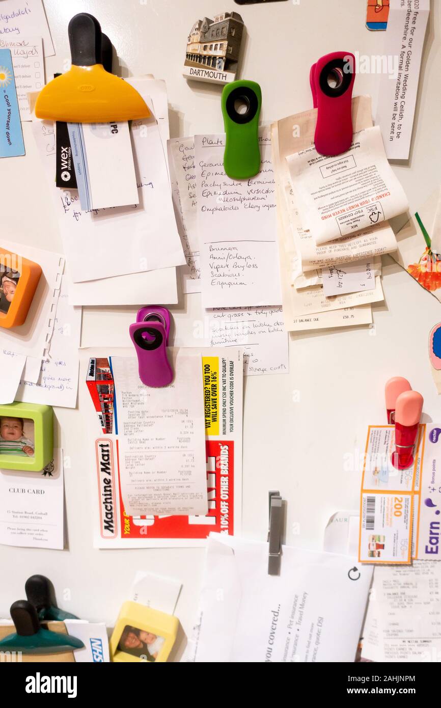 Lettere e note, le ricevute, gli elenchi e le schede aziendali attaccato al lato di un frigorifero con magneti per il frigo Foto Stock