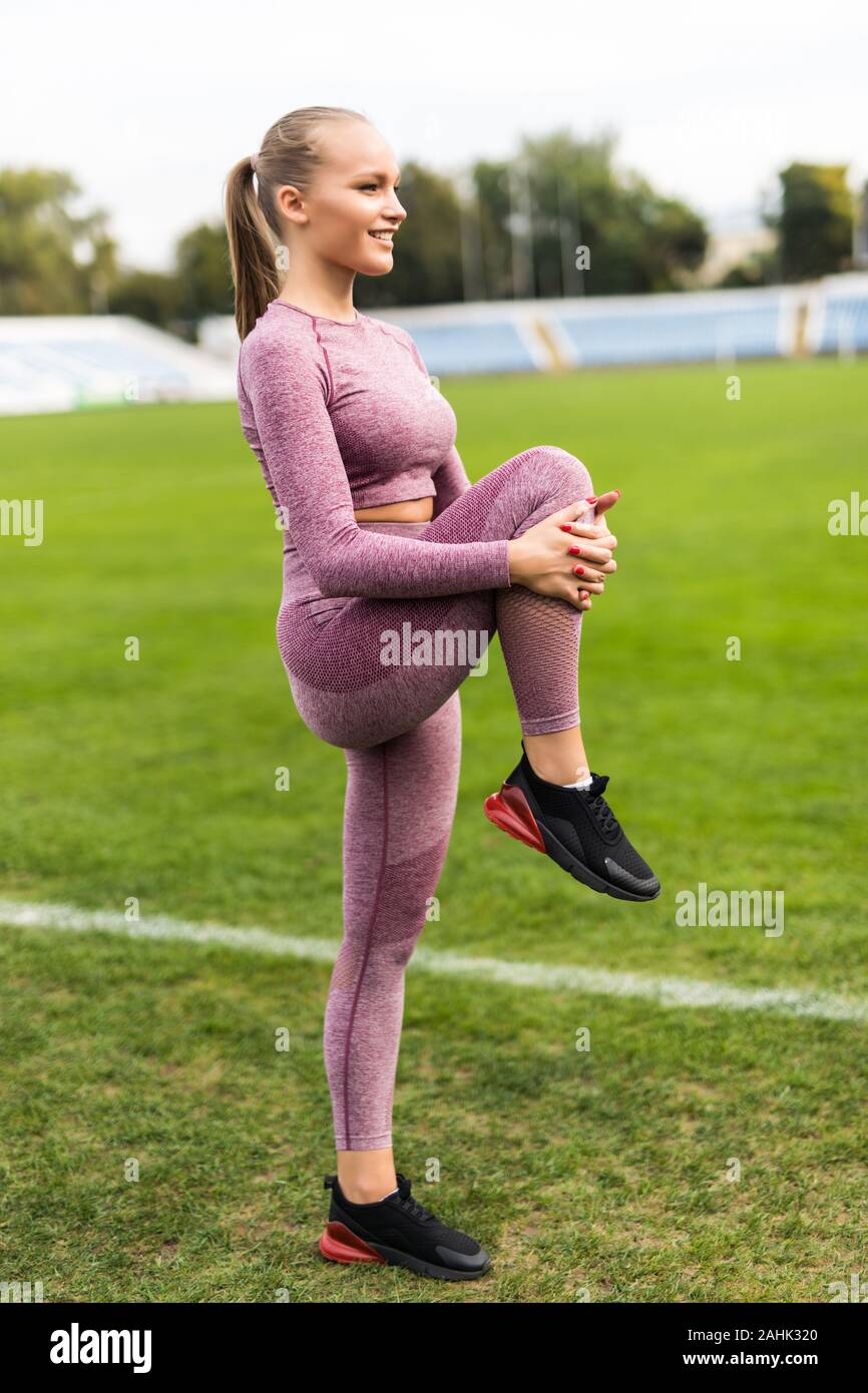 Velocista donna in abbigliamento sportivo facendo il warm-up esercizi con  le gambe prima di eseguire sul Stadium Foto stock - Alamy