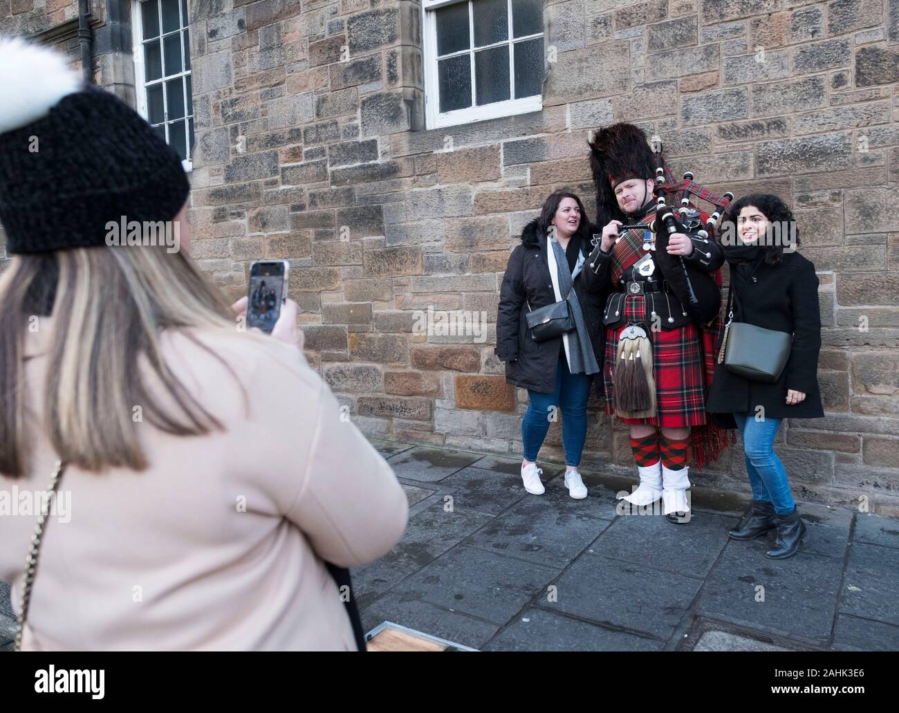 Tourist fotografando un piper musicista di strada sul Royal Mile di Edimburgo, Scozia. Foto Stock