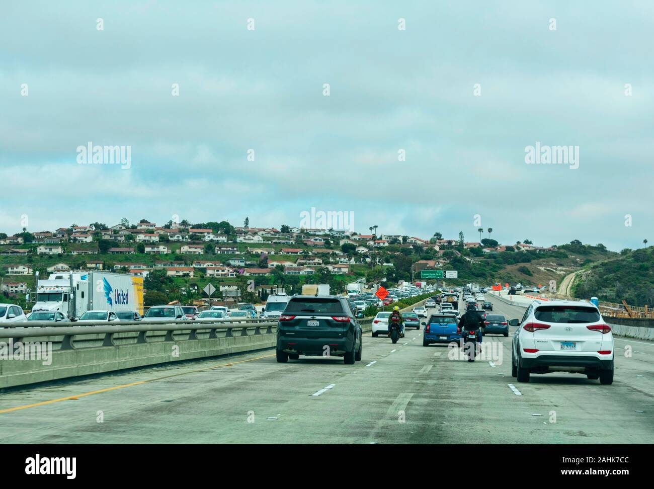 I motociclisti che passa più lento del traffico per la guida di un motociclo in corrispondenza dello spazio tra due corsie parallele del traffico nella stessa direzione Foto Stock