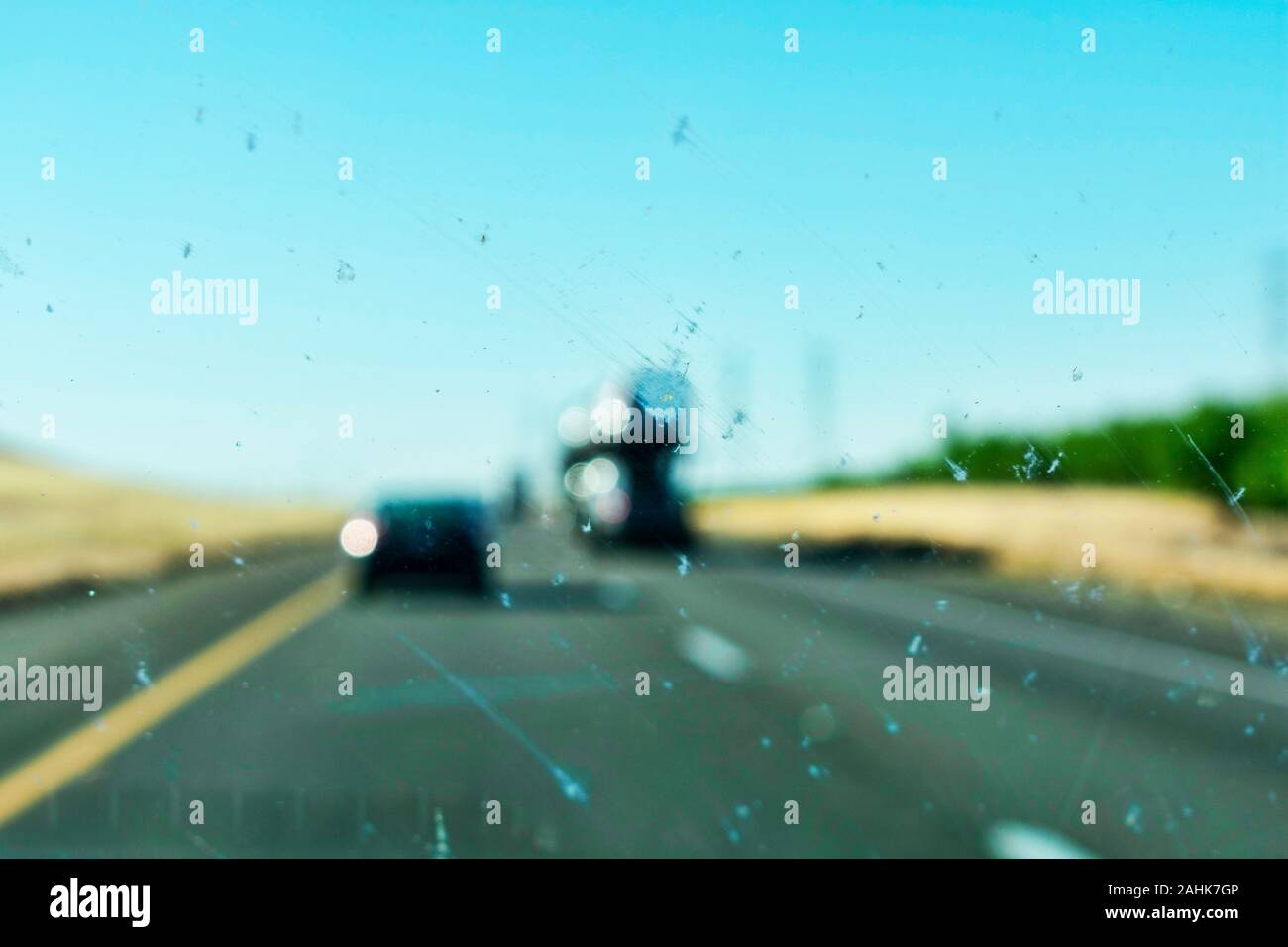 Macchina sporca vetro per finestra con gli insetti e sporcizia influiscono sulla visibilità del conducente durante la guida su autostrada diviso. Il usurato o guasto auto spazzole tergicristallo. Foto Stock