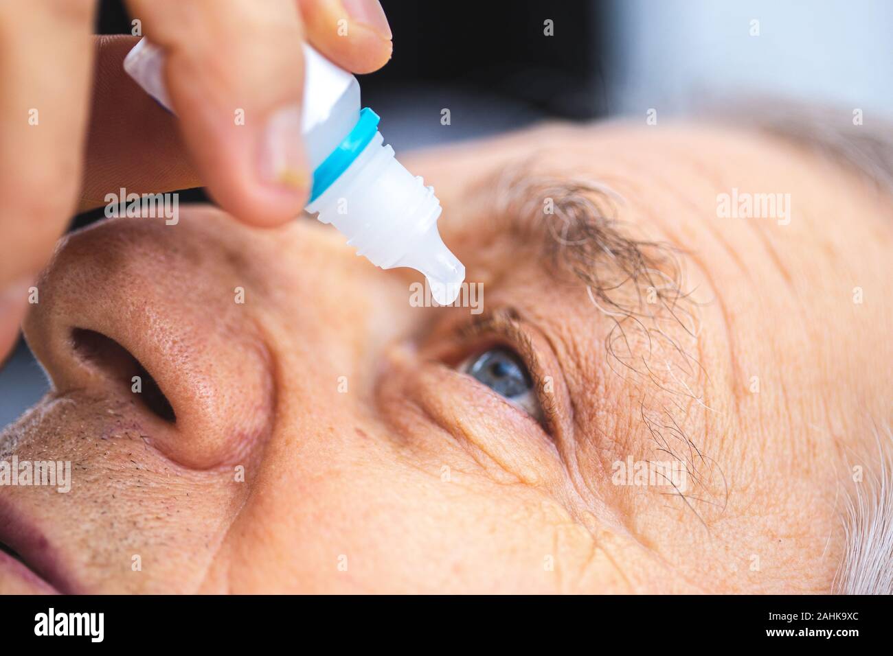 Persona anziana mette collirio nell'occhio. Senior uomo mettendo in gocce per gli occhi Foto Stock