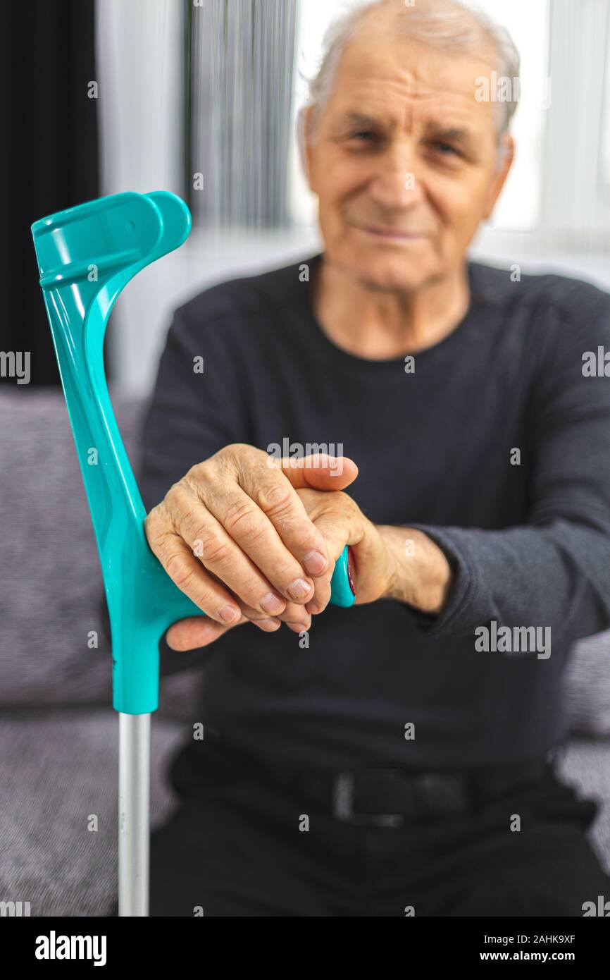 Persona anziana in piedi con le mani appoggiate sul medical bastone. Concetto di persona con immobilità, giunti, reumatismi problema. Foto Stock