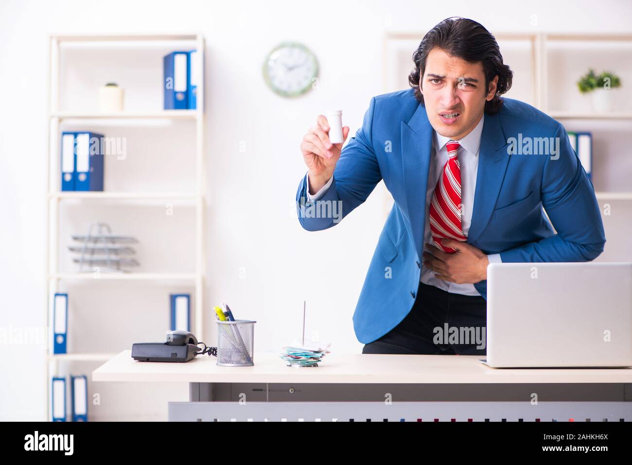 Il giovane maschio sofferenza dei dipendenti in ufficio Foto Stock