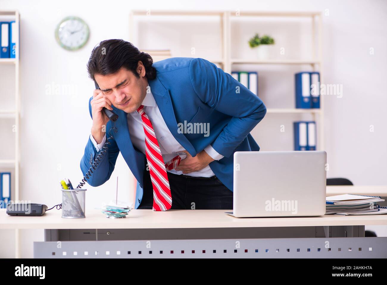 Il giovane maschio sofferenza dei dipendenti in ufficio Foto Stock