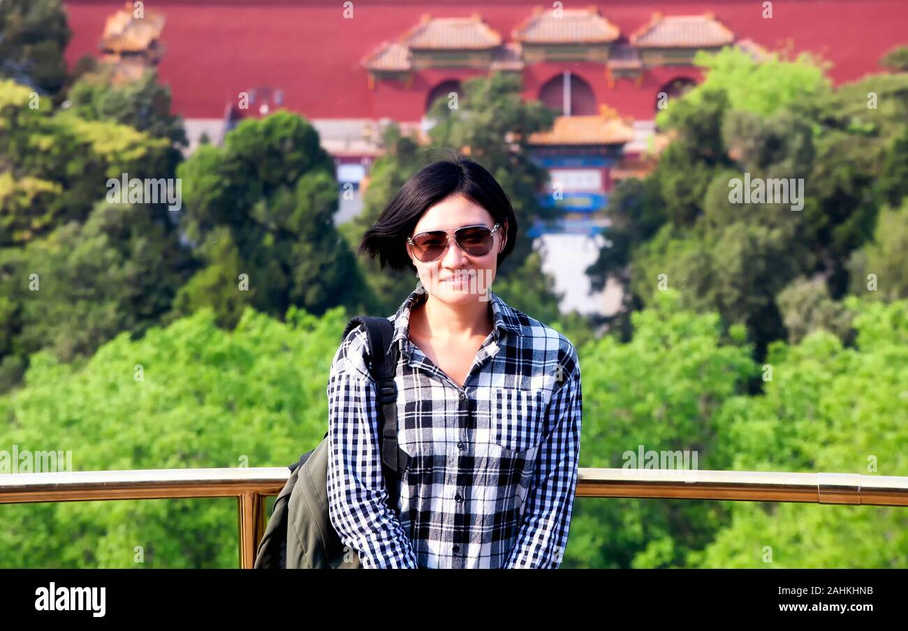 Un felice donna cinese che indossa un bianco e nero plaid shirt sopra Parco Jingshan a Beijing in Cina in una giornata di sole. Foto Stock Un felice donna cinese che indossa un bianco e nero plaid shirt sopra Parco Jingshan a Beijing in Cina in una giornata di sole. Foto Stock