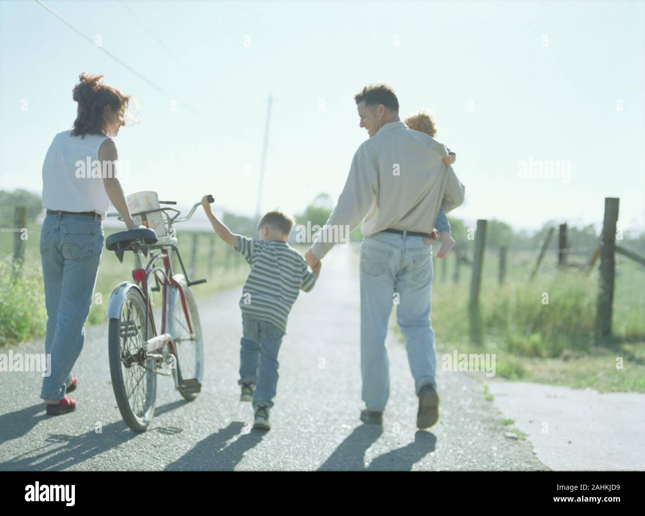 Una famiglia felice è una passeggiata a piedi lungo una strada di campagna. Foto Stock